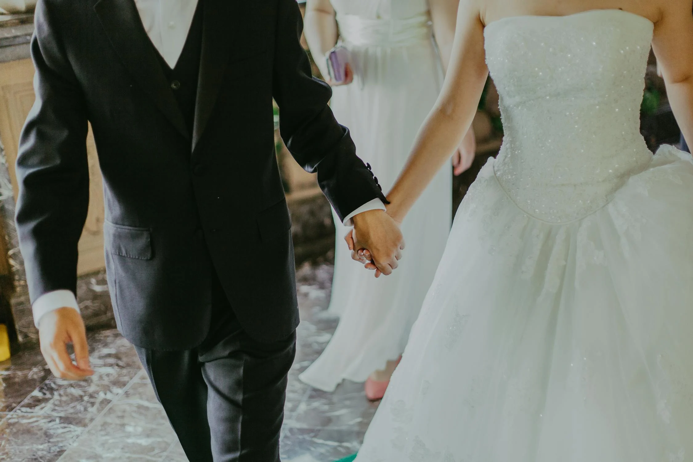 A husband and wife holding hands walking down the aisle.